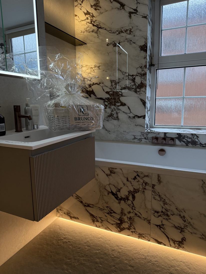 Fitted bath with marble panel and bronze taps
